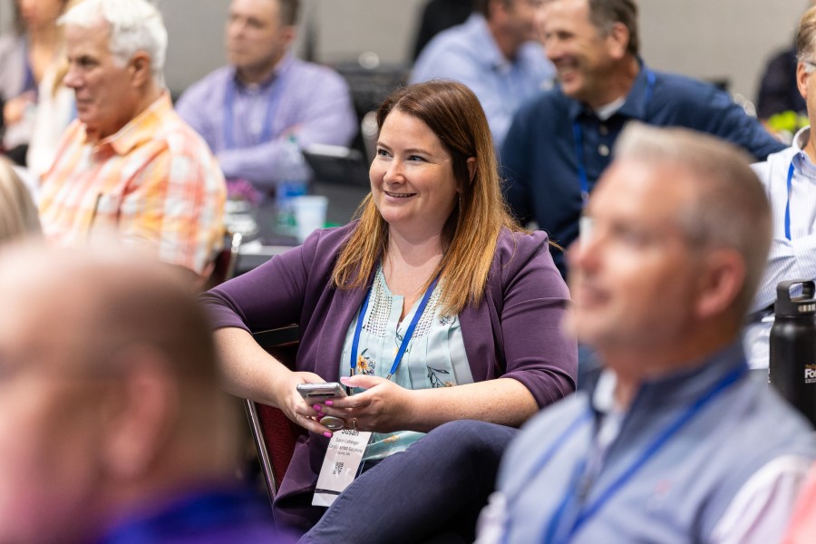 A woman sitting in a crowd listening to a speaker